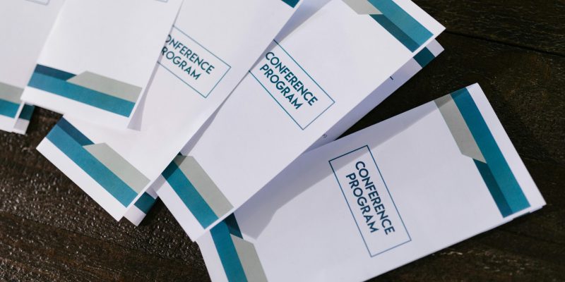 Close-up of neatly arranged conference program pamphlets on a wooden surface, suitable for professional and business settings.